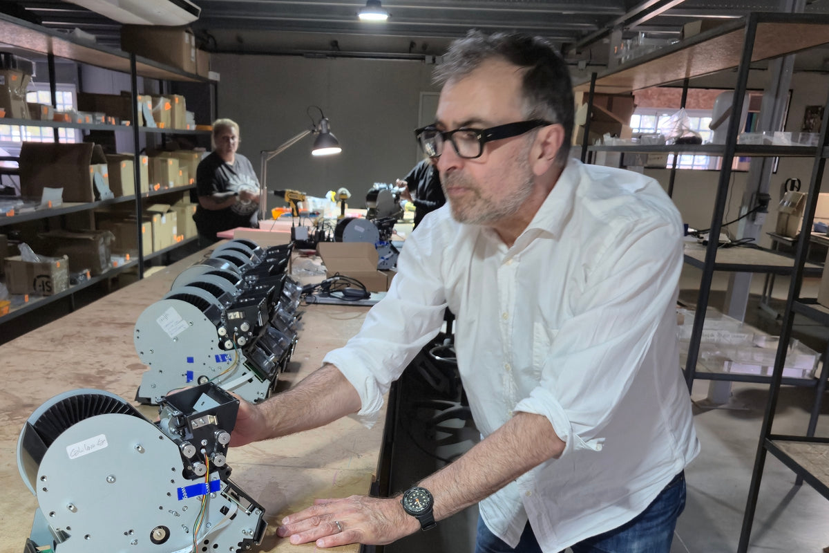 François penché sur une rangée de mécanismes LeShuffler à l’établi de l’atelier